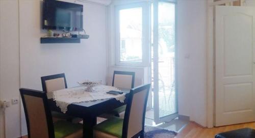 a dining room with a table and chairs and a television at Apartman Pazova in Soko Banja