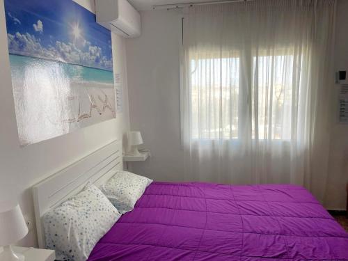 a bedroom with a purple bed and a window at CALAFELL 5 BEACH in Calafell