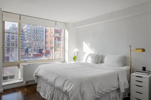 - une chambre blanche avec un grand lit et une fenêtre dans l'établissement Luxury Private Apt New York City View, à New York