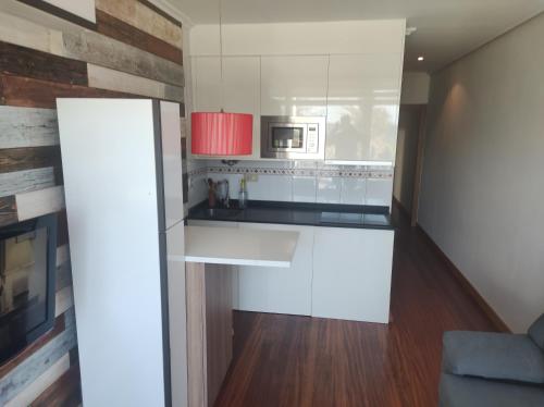 cocina con armarios blancos y microondas en APARTAMENTO EN LINEA DE PLAYA, en Suances