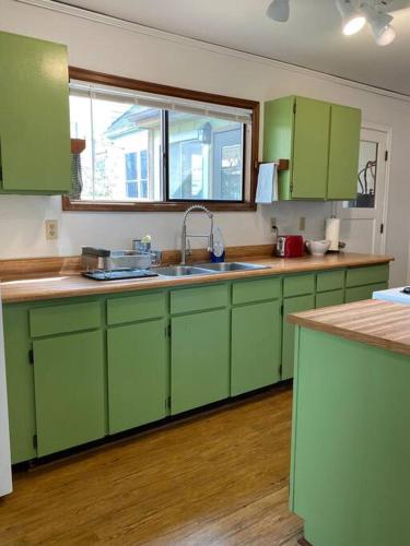 a kitchen with green cabinets and a sink at Quaint Downtown Cottage in Astoria, Oregon
