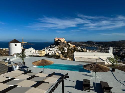 a pool with umbrellas and a view of a city at O Mylos in Ermoupoli