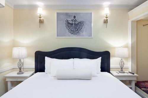 a bedroom with a large white bed with two lamps at Hotel la Perla Leon in León