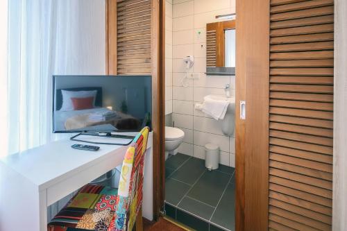 a bathroom with a sink and a toilet and a bedroom at Hotel Saarlouis am kleinen Markt in Saarlouis