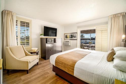 1 dormitorio con 1 cama, 1 silla y TV en Little Inn By The Bay Newport Beach Hotel en Newport Beach