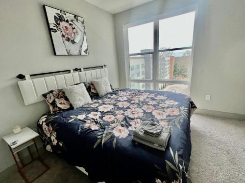 a bedroom with a bed with a floral blanket and a window at Luxury Sky-rise Penthouse with Rooftop Deck and Pool in Atlanta
