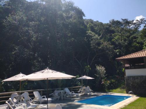 - une piscine avec des chaises et des parasols à côté dans l'établissement Pousada dos Anjos, à São Pedro da Serra