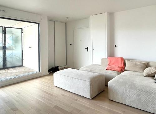 - un salon avec un canapé et un pouf dans l'établissement Appartement 2 pièces 30min du centre de Paris, à Clichy