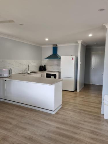a white kitchen with a sink and a refrigerator at Banksia Villa's Kingaroy in Kingaroy