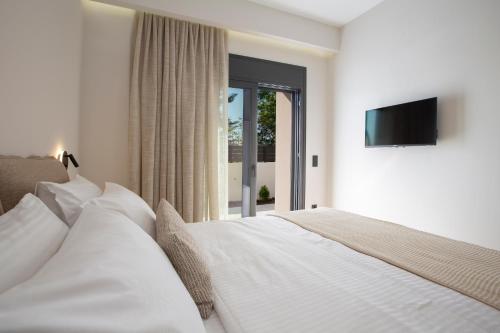 a bedroom with a white bed with a television on the wall at Pomaria Boutique Residences in Lefkada Town