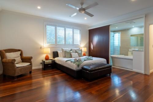 ein Schlafzimmer mit einem Bett, einem Stuhl und einem Fenster in der Unterkunft Malibu Beach House in Kingscliff