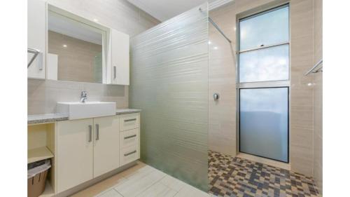 ein Bad mit einer Dusche, einem Waschbecken und einem Spiegel in der Unterkunft Malibu Beach House in Kingscliff