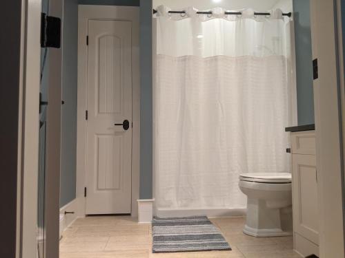 a bathroom with a white shower curtain and a toilet at Mountain House of Wonder in Qualicum Beach