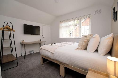 1 dormitorio con cama con almohadas y ventana en Hall Lane House - Stunning 4Bed 5 mins Walk to Coventry Hospital, Must See!, en Coventry
