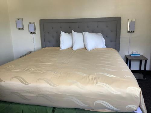 a large bed with white pillows in a hotel room at National 9 Motel in Santa Cruz