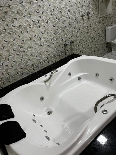 uma banheira branca numa casa de banho com azulejos em Pousada Rota dos Macacos em Nova Lima