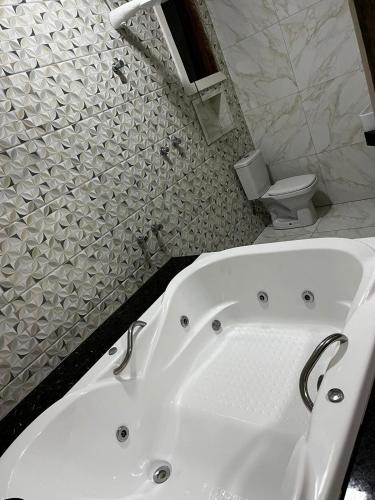 Pousada Rota dos Macacos في نوفا ليما: حوض استحمام أبيض في حمام مع مرحاض