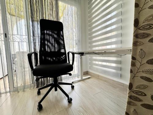 a black office chair sitting in a room with windows at Relaxing Ocean View, Spacious Art Apartment With Large Terrace, Near Best Costa Adeje Beaches in Adeje
