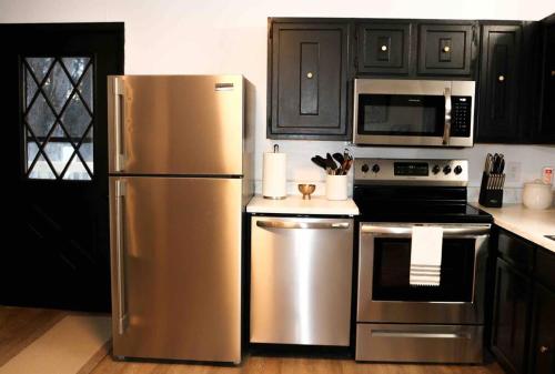 una cocina con electrodomésticos de acero inoxidable y armarios negros en The New Luxury Cabin PetFriendly Pocono Summit en Pocono Summit