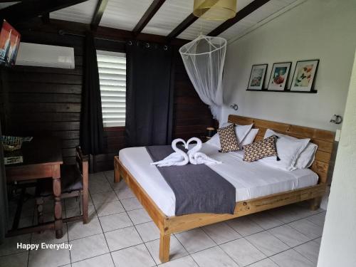 una camera da letto con un letto con un nastro sopra di La Colline Verte a Deshaies