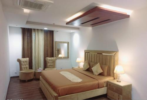 een slaapkamer met een groot bed en 2 stoelen bij 2 bed Apartment in Gold crest apartment in Lahore