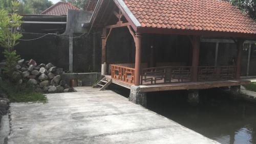 a building with a wooden walkway next to a body of water at Griya Nareswara in Piyungan