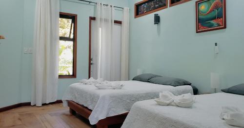a bedroom with two beds with white sheets and a window at Villa Akala in Cocles