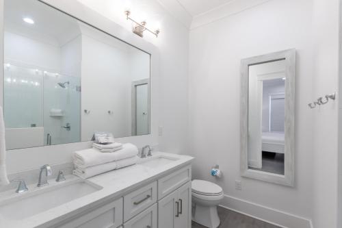 a white bathroom with a toilet and a large mirror at Beach Village Resort By Liquid Life in Gulf Shores