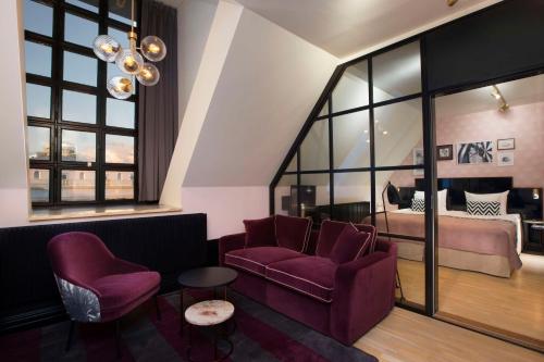 a living room with purple chairs and a bed at Haymarket by Scandic in Stockholm