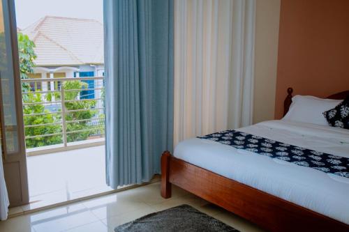 a bedroom with a bed and a window with a balcony at Gmasters Homes kibagabaga in Kigali