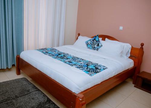 a bed with white sheets and blue pillows on it at Gmasters Homes kibagabaga in Kigali