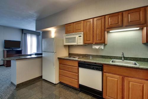 a kitchen with wooden cabinets and a white refrigerator at Drury Inn & Suites San Antonio Northwest Medical Center in San Antonio