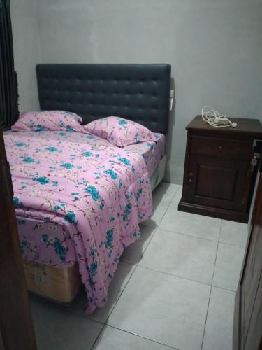 1 dormitorio con cama rosa y mesita de noche de madera en Homestay Aisyah Bromo, en Probolinggo