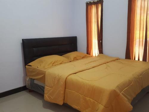 1 dormitorio con 1 cama con edredón amarillo en Homestay Aisyah Bromo, en Probolinggo