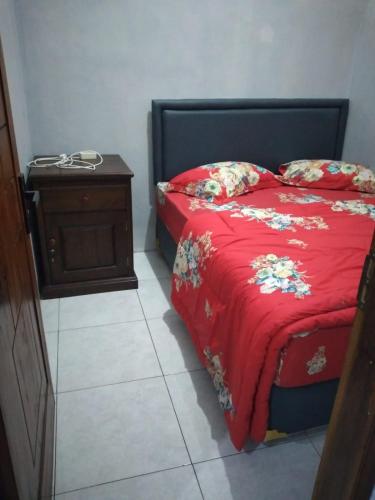 1 dormitorio con 1 cama con manta roja y mesita de noche en Homestay Aisyah Bromo, en Probolinggo