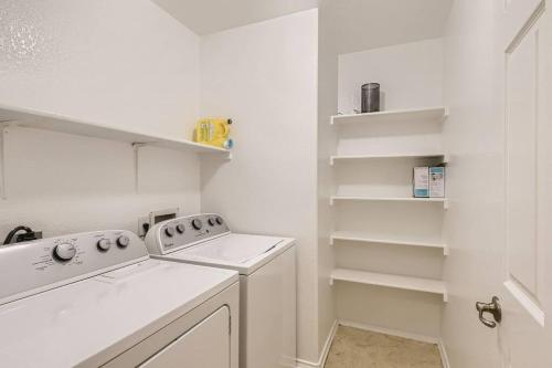 a white laundry room with a washing machine and shelves at Hidden Gem near F1! 3bd/2bath - Private Backyard! in Austin