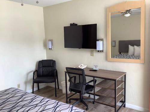 Habitación con escritorio, silla y espejo. en National 9 Motel en Santa Cruz