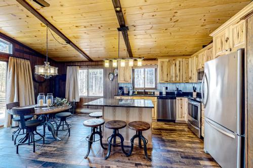 a kitchen with a refrigerator and a table with stools at Big Woods Hideaway in Saint Germain