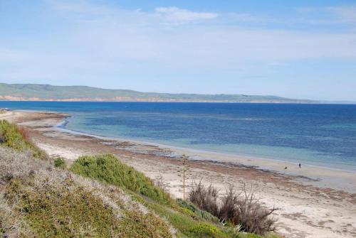 una playa con gente caminando en el agua en The ReTrO Beach Shack, en Aldinga Beach