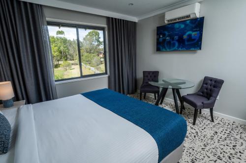 a hotel room with a bed and a table and a window at Warners at the Bay in Warners Bay