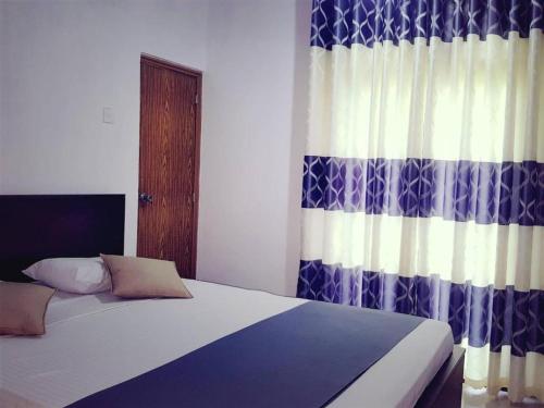 a bedroom with a bed with a blue and white curtain at Limitless in Sri Jayewardenepura Kotte