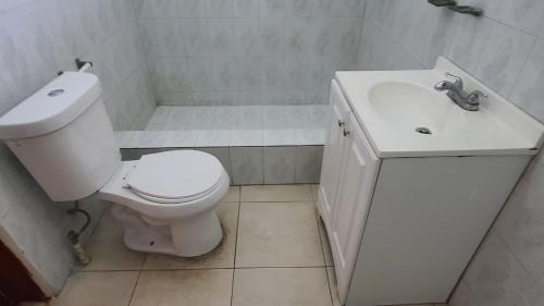 a bathroom with a white toilet and a sink at Super Two Bedroom Penthouse in Peguy-Ville in Port-au-Prince