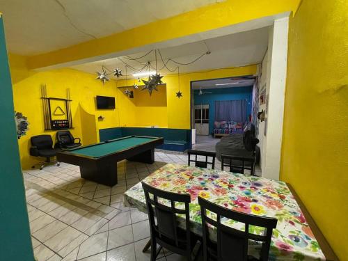 un salon avec une table de ping-pong et des murs jaunes dans l'établissement Casa frida a 2 minutos del malecón, à Puerto Vallarta