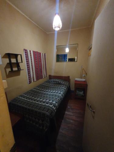 a small room with a bed and a mirror at Hospedaje Frankenstein in Cusco