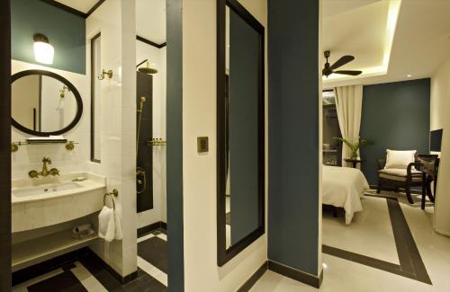 a bathroom with a sink and a mirror and a bedroom at Maison Vy Hotel in Hoi An