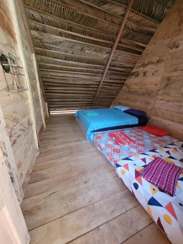 a room with two beds in a wooden floor at Pachamaya Hostel in Lanquín