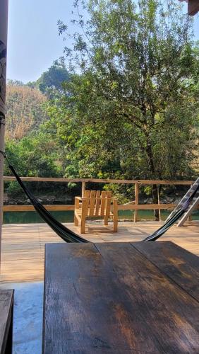 a hammock on a deck with a bench and a tree at Pachamaya Hostel in Lanquín