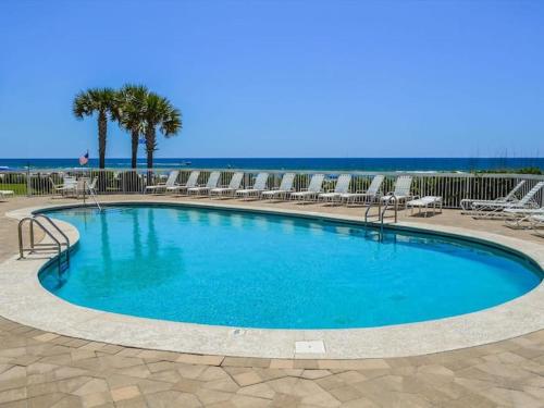 a large swimming pool with chairs and the ocean at Welcome to Gone Coastal! - Walk to Beach in Orange Beach