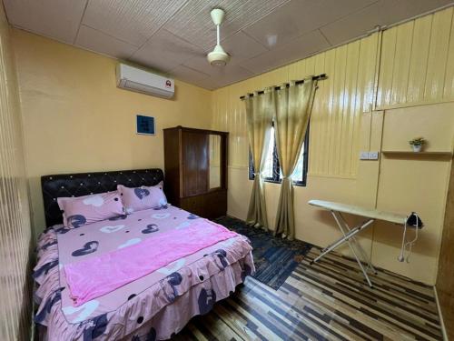 a bedroom with a pink bed and a desk at Homestay Ummie 