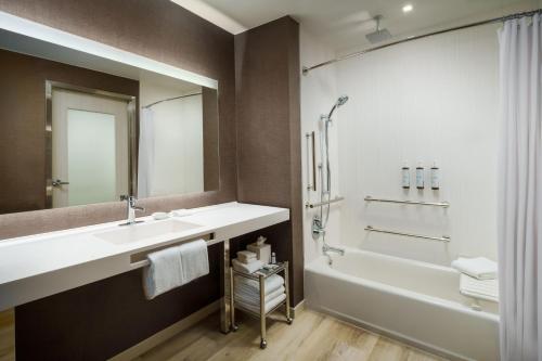 a bathroom with a sink and a tub and a shower at AC Hotel by Marriott Jacksonville St Johns Town Center in Jacksonville